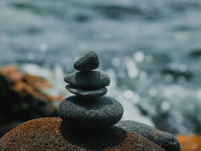 Smooth stones stacked on a blurred background of green leaves.